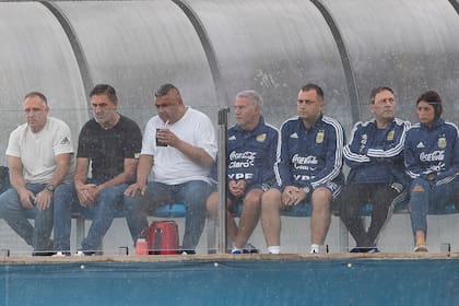 Chiqui Tapia y parte de la delegación, se protegen de la lluvia, durante el entrenamiento de esta mañana