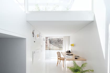 El entrepiso resulta un agradable rincón de trabajo que se abre a la circulación central y a un ventanal pivotante de piso a techo y de pared a pared. Escritorio (Somos Nu). Toda la casa está pintada con pintura látex lavable ‘Perma-White’ (Zinsser).