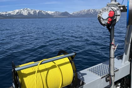 El equipo opera el robot que recoge desechos del lago desde una embarcación en la superficie