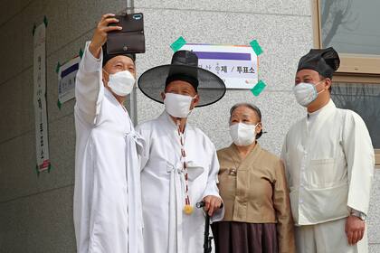 El erudito confuciano surcoreano Yoo Bok-Yeob y los miembros de su familia con traje tradicional posan para una selfie después de emitir su voto para las elecciones parlamentarias en un colegio electoral en Nonsan el 15 de abril de 2020
