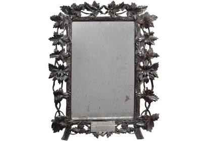 El espejo mide cincuenta por cuarenta centmetros y est rodeado por un marco de madera de nogal tallada con forma de enredadera