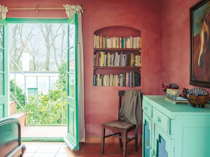 El estucado en rosa, color muy usado en la arquitectura colinial pampeana, pasa de la pared al nicho que contiene la biblioteca sin marcos de por medio.