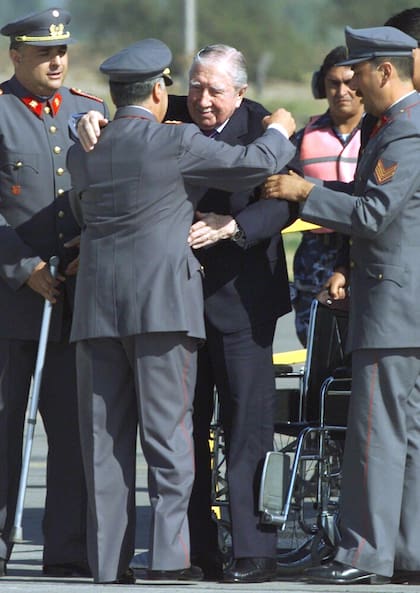 El ex dictador chileno Augusto Pinochet (izquierda) es ayudado a levantarse de su silla de ruedas por el comandante en jefe del Ejército de Chile, general Ricardo Izurieta (de frente a Pinochet), en la pista del aeropuerto militar local, momentos después de llegar desde Londres, el 3 de marzo /Photo by Rickey Rogers REUTERS