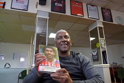 El ex jugador de fútbol inglés Ricky Hill posa con una copia de su libro en Luton, Inglaterra, para hablar de la falta de diversidad en puestos de entrenador 