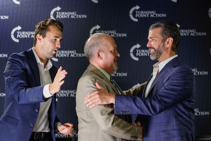El exfiscal general de Wisconsin y candidato a la Corte Suprema del estado Brad Schimel, en el centro, saluda a Donald Trump Jr, mientras Charlie Kirk mira durante un encuentro público el lunes 17 de marzo de 2025, en Oconomowoc, Wisconsin. (AP foto/Jeffrey Phelps)