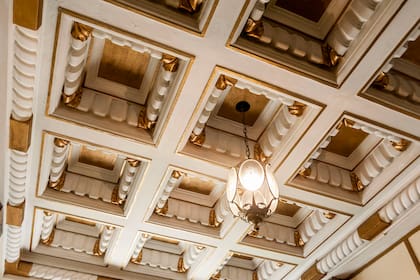 El extenso cielorraso del hall posee un trabajo de yesería denominado casetonado en dorado y blanco