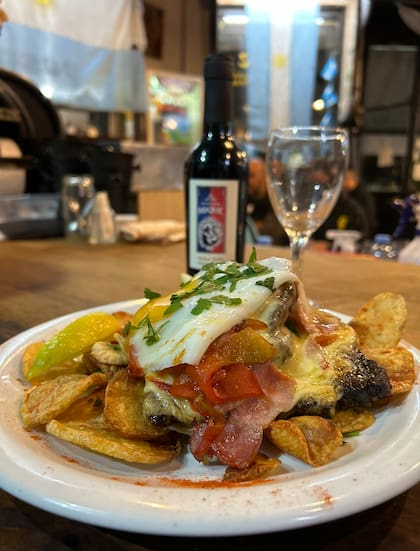 El famoso "alfajor salado" de Roque: torres finas de lomo, panceta y provoleta gratinada sobre colchón de papas españolas