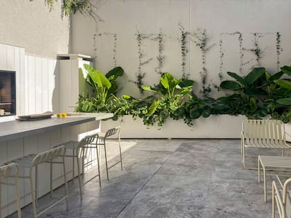 El frente de la barra y la pared que contiene la parrilla se revistieron con placas de siding (Cedral). Mesada de cemento alisado. Banquetas, banco y mesa ‘Patrón’ (El Yeite).