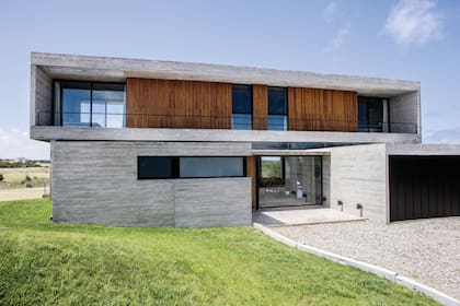 El frente de la propiedad muestra un basamento cerrado, con el acceso retirado, que busca desdibujarse en el entorno.