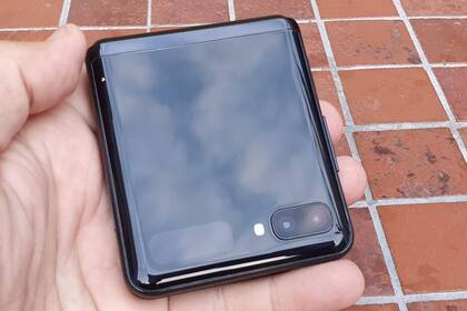 El frente del teléfono cuando está cerrado, con la doble cámara principal, el flash, y una pequeña pantalla que muestra la hora y las notificaciones