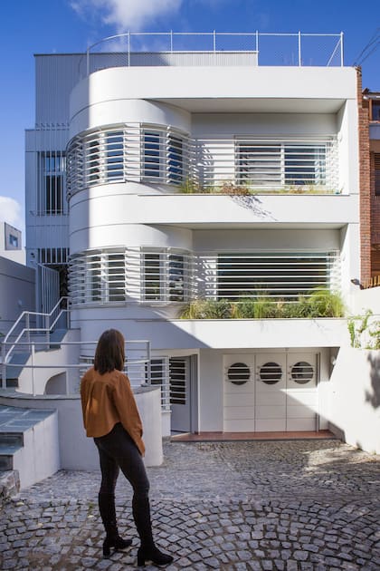 El frente muestra el garage con tres puertas con ojos de buey; el primer piso, donde está la puerta de entrada a la que se llega por la escalera lateral. El segundo piso tiene los dormitorios y, arriba de todo, están los nuevos estudios de los dueños de casa.