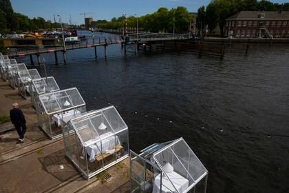 El fundador y director del restaurante Mediamatic Willem Velthoven, a la izquierda, atiende a clientes que almuerzan en pequeños invernaderos en Amsterdam, Países Bajos, el lunes 1 de junio de 2020.