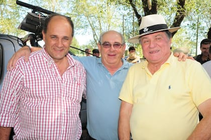 El ganadero cordobés José Luis "Gringo" Grimaldi (con camisa amarilla) junto a otros dos productores en una subasta ganadera