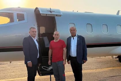 El gendarme Nahuel Gallo, de rojo, al pie del avión que lo trajo de Venezuela junto a dos funcionarios de la AFA