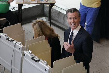 El gobernador de California, Gavin Newsom, reacciona cuando mira hacia arriba y ve a los fotógrafos que lo capturan a él y a su esposa, Jennifer Siebel Newsom, a la izquierda de la votación en un centro de votación en Sacramento, California, el martes 8 de noviembre de 2022