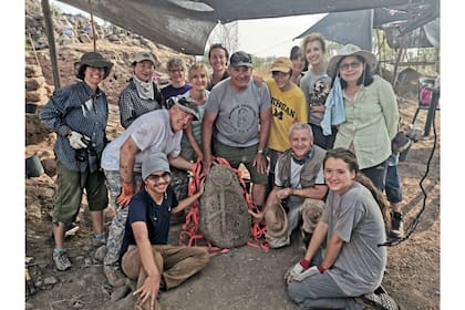 El grupo de arqueólogos reunidos junto a una pieza que representa a la luna