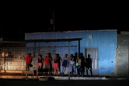 Vecinos observan a miembros de la FAES mientras detienen a personas durante un patrullaje nocturno en Barquisimeto