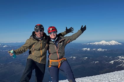 El guía Insarralde, con una turistas, en la cima del volcán, desde donde se observan otros picos