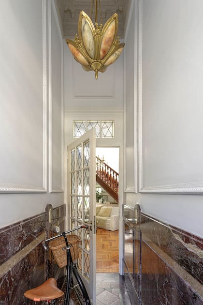 El hall de acceso, revestido en mármol y con lámpara de ónix de los años 20 que Carolina encontró online.