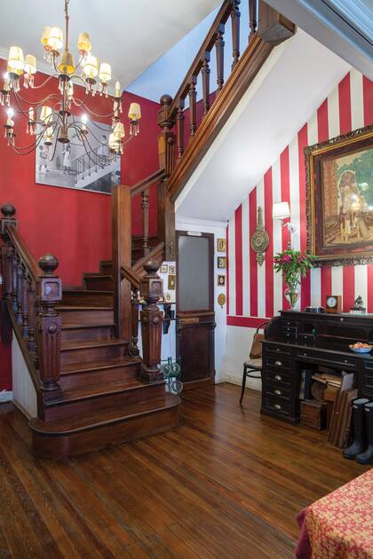 El hall de distribución, con una pared a rayas en composé con la que acompaña la imponente escalera de madera.