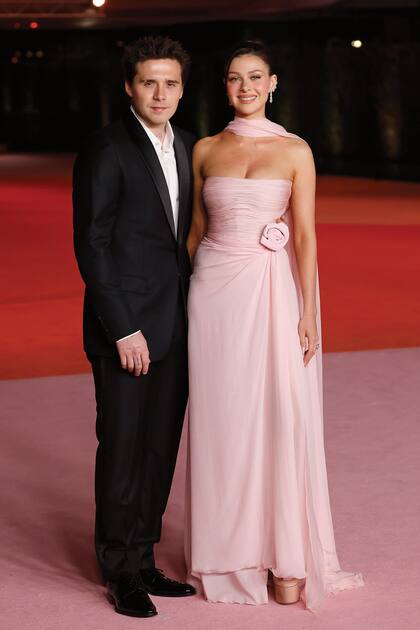 El hijo de David y Victoria Bechham, Brooklyn Beckham, posó junto a su mujer, Nicola Peltz, que vistió un traje Valentino en rosa empolvado de cuerpo drapeado y falda vaporosa y un fulard haciendo juego. Lo combinó con zapatos con plataforma de la misma firma italiana. 
