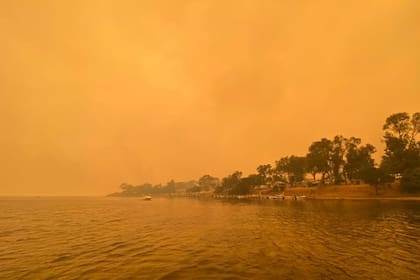 El humo de los incendios forestales salvajes envuelve el cielo en Mallacoota, Victoria, Australia, el 31 de diciembre de 2019. Las informaciones de varias zonas turísticas dan cuenta de miles de turistas y lugareños que pasaron la Nochevieja a orillas del mar, acorralados por las llamas.
