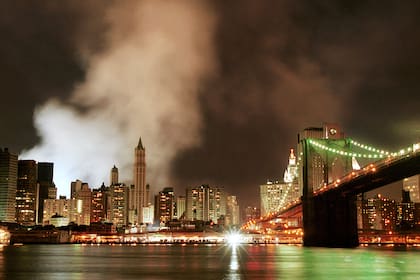 El humo de los restos humeantes del World Trade Center ondea sobre el horizonte del Bajo Manhattan, recortando la silueta del edificio Woolworth, en el centro, la madrugada del domingo 16 de septiembre de 2001