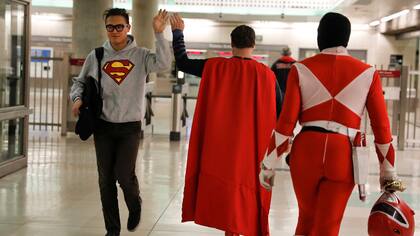 El imitador de Superman Justin Harrison, centro, saluda a un ocasional transeúnte el cual lleva un remera con un símbolo de Superman impreso ,de regreso a sus casas después de trabajar en Hollywood Boulevard junto a su compañero de cuarto, Reginald Jackson, vestido con un traje de Power Ranger rojo.