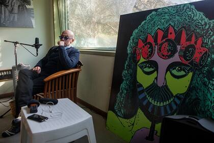El Indio Solari en su estudio durante la entrevista, sentado al lado de un cuadro de su autoría