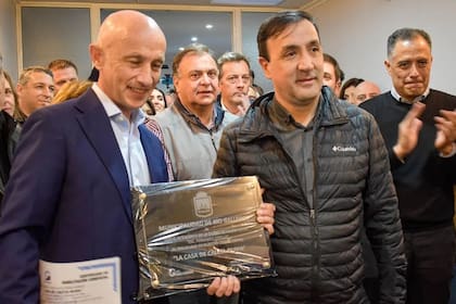El intendente de Caleta Olivia, Fernando Cotillo, recibe una placa de manos de Pablo Grasso, intendente de Río Gallegos