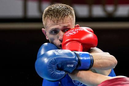 El irlandés Kurt Anthony Walker recibe un puñetazo del español José Quiles Brotons durante el combate de boxeo preliminar de plumas masculinas (52-57 kg) durante los Juegos Olímpicos de Tokio 2020 en el Kokugikan Arena de Tokio el 24 de julio de 2021.