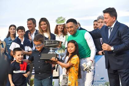 El jockey William Pereyra, junto a su hija, en la entrega de premios, tras el susto.
