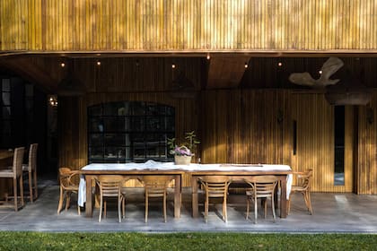 El juego de comedor se hizo con la madera de una araucaria que había en el terreno. A la izquierda, junto a la parrilla, está la entrada al taller de Caro.