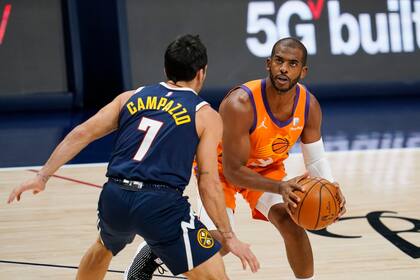 El jugador de los Suns de Phoenix Chris Paul (derecha) se prepara para un lanzamiento ante su rival de los Nuggets de Denver Facundo Campazzo, en la primera mitad del juego de la NBA que enfrentó a ambos equipos, el 1 de enero de 2021, en Denver.