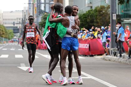 El keniano Eliud Kipchoge abraza a Abdi Nageeye y a Bashir Abdi; el neerlandés y el belga se combinaron para dejar fuera del podio a Lawrence Chirono, también de Kenia, que llega con desazón a la meta.