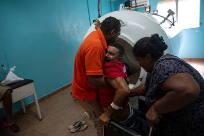 Misael Banegas Diaz, de 49 años es asistido por el fisioterapeuta Cedrak Waldan Mendoza y su esposa, al salir de la cámara hiperbárica