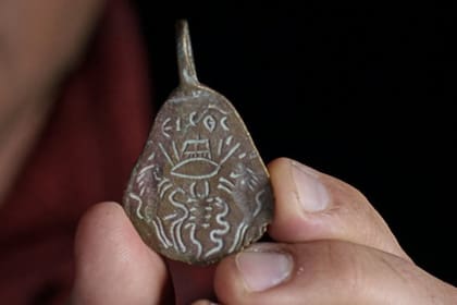 El lado opuesto del objeto presenta un ojo atravesado por flechas y rodeado de animales peligrosos