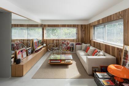 El living-comedor les quedaba demasiado alargado: agregando un espejo en la pared lateral, lograron ensancharlo visualmente. Consola y mesa de centro a medida (Margen)