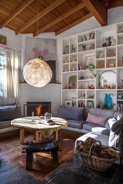 El living conserva su impronta de los 70, con desnivel, hogar y sillones curvos de obra,
pero los textiles y los objetos decorativos le dan un aire fresco y contemporáneo. La lámpara lunar es de Akelik Home.