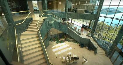 El living exhibe tres de los cinco pisos de la casa con un piano de cola blanco y dos escaleras gemelas quedestacan el diseño que le valió el apodo de “la mansión más fea del mundo”