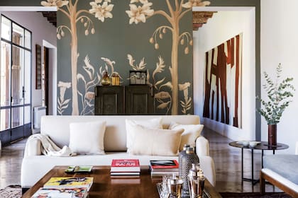 El living se completa con un dúo de sillones individuales heredados, sofá ‘Gaucho pop’ y camastro ‘Cunga’ (ambos de Naturaleza Aguirre). La mesa ratona de lenga se encargó para una casa anterior a un carpintero de San Martín de los Andes. Obra de Isabel Luis y alfombras traídas de Marruecos.