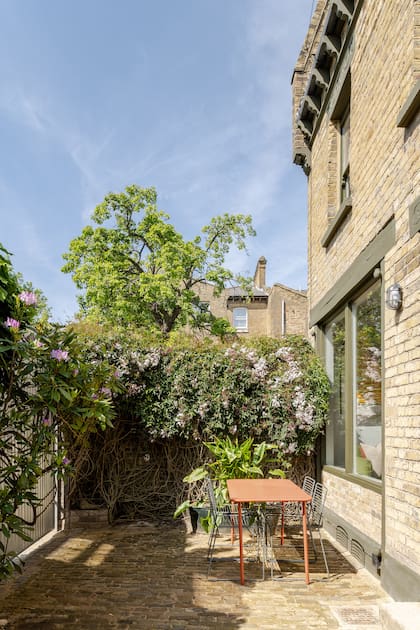 El living se conecta al pequeño jardín interno que da a la calle, equipado con una mesa y sillas para almorzar al sol.