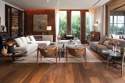 El living tiene diferentes spots, como el del piano, el de los vinilos, donde se destaca una pared revestida en piedra bronzite rugoso. Los ventanales, que se abren de punta a punta, logran un espectacular efecto in/out