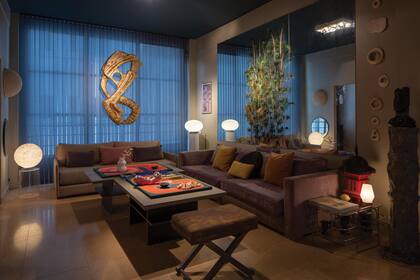 El living tiene varias intervenciones de Gerardo, como las plumas de pavo real en el espejo, o la obra sobre la ventana, una talla que evoca el arte de los años 60 presentes en los murales o interiores de los edificios de esa época. “El edifico fue construido por Antonio Ubaldo Vilar, gran referente del movimiento racionalista en Argentina”, cuenta el decorador de eventos.