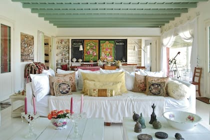 El living y el comedor comparten un gran ambiente que se comunica directamente con la galería con parrilla, por un lado, y con el río, por el otro. Al fondo, detrás de la cortinas, la cocina.