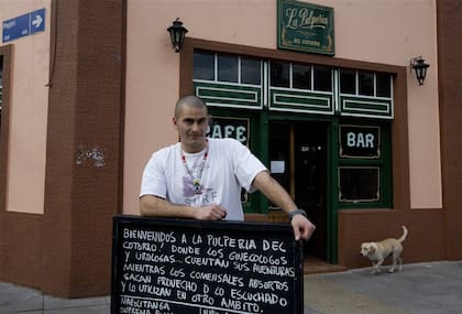 Julián Mazzeo, dueño de la pulpería, junto a uno de sus carteles