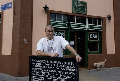 Julián Mazzeo, dueño de la pulpería, junto a uno de sus carteles