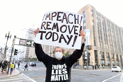 El manifestante Kenneth Lundgreen sostiene un cartel que pide la destitución del presidente Donald Trump mientras la policía armaba barricadas frente a la sede corporativa de Twitter en San Francisco, California, el 11 de enero de 2021