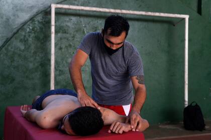 Fulvio Duarte masajea a un voluntario en el gimnasio de la Universidad San Roque González, San Lorenzo; hace un año que no cobra su sueldo como jugador