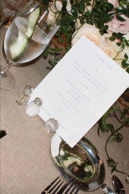 El menú, que se encontraba frente a cada plato. Las mesas estaban adornadas con arreglos de rosas y velas blancas.